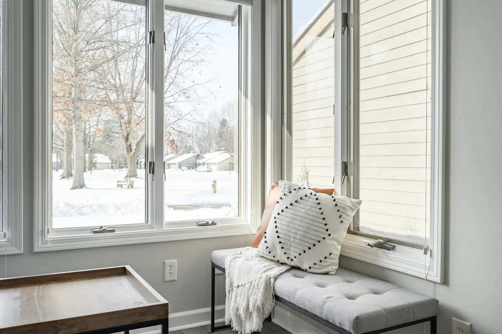 Tilt & Turn Windows in Newcastle upon Tyne Window seat with cushions beside a large white window, illustrating tilt & turn windows for homes in Newcastle upon Tyne
