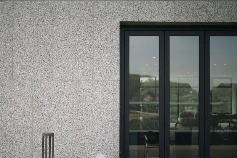 uPVC vs aluminium windows in Newcastle upon Tyne Black-framed glazed doors in a grey rendered wall, illustrating uPVC vs aluminium windows for homes in Newcastle upon Tyne