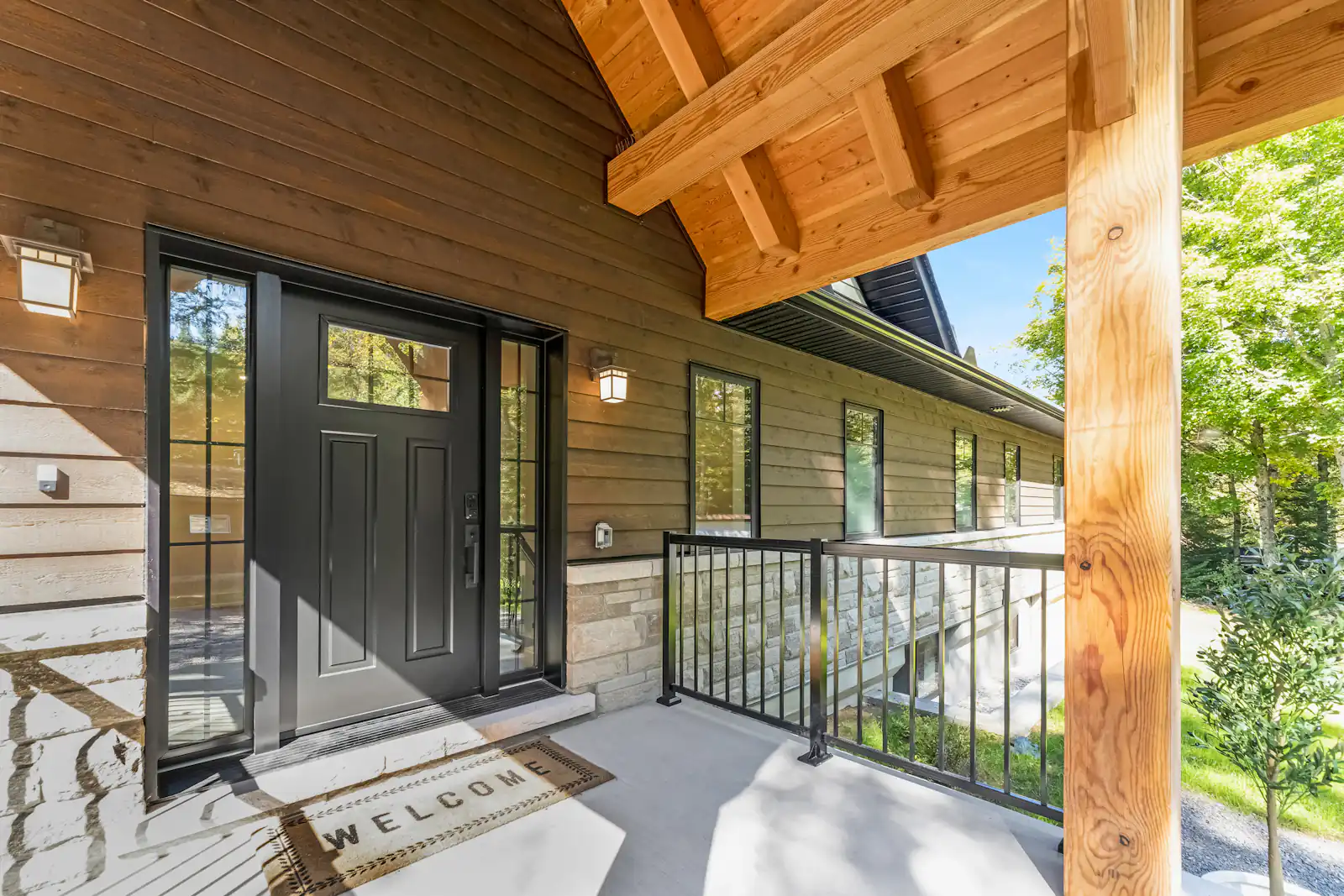 Window and door costs in Newcastle upon Tyne Timber-clad house with dark glazed doors and a covered porch, illustrating window and door costs for homes in Newcastle upon Tyne