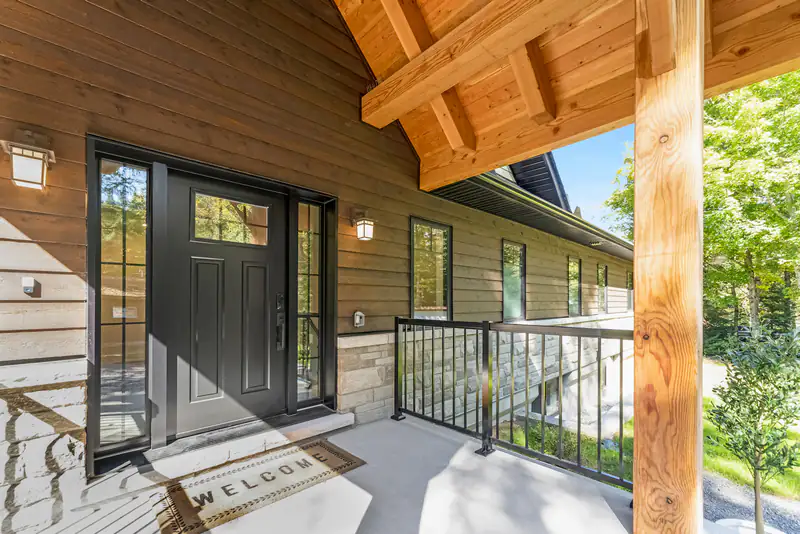 Window and door costs in Newcastle upon Tyne Timber-clad house with dark glazed doors and a covered porch, illustrating window and door costs for homes in Newcastle upon Tyne